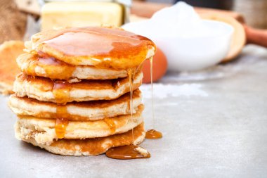 Mutfak masasında taze krep ve şurup damlıyor.