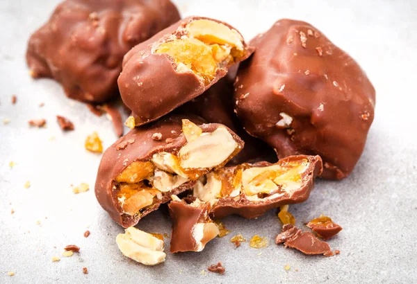 Chocolate covered peanut brittle pieces on grey