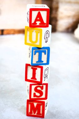 Autism spelled out in kids building blocks on mottled grey clipart