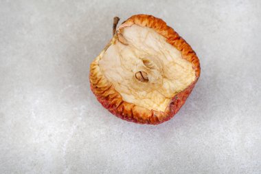 Kurumuş elmanın yarısı benekli gri üzerinde. 