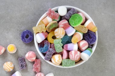 Benekli gri yüzeyde bir kase karışık jöle şekeri. Kopyalama alanı olan düz