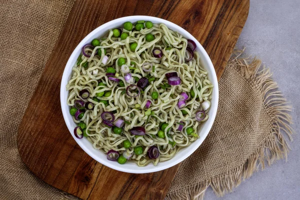 Spinach and kale Ramen noodles with spring onion, peas rustic wood and burlap surface with copy space