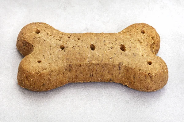 single large dog biscuit in bone shape on mottled grey