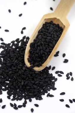 Tahta kepçeli siyah susam tohumları kopyalama alanı ile beyaza izole edilmiş.