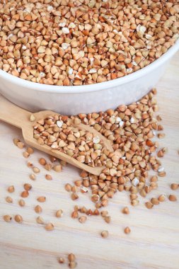 Hafif ahşap yüzeyde kepçeyle kabuklu karabuğday, üst manzara.