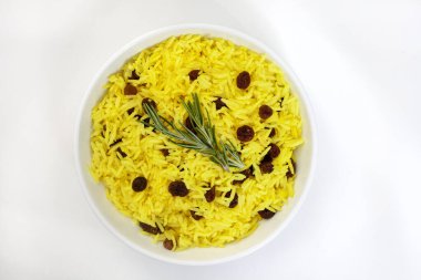 Geleneksel Güney Afrika sarı pirinci, zerdeçal ve biberiye garnitürle yapılan kuru üzümler, beyaz üzerine izole edilmiş yuvarlak kasede.