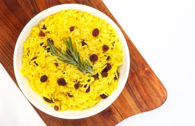 Geleneksel Güney Afrika sarı pirinci, zerdeçal ve biberiye garnitürlü kuru üzümler, rustik ahşap tahtalı yuvarlak kase. Kopyalama alanı olan üst görünüm ya da düz uzanma