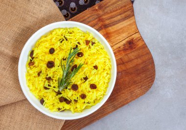 Geleneksel Güney Afrika sarı pirinci, zerdeçal ve biberiye garnitürlü kuru üzümler, rustik ahşap tahtalı yuvarlak kase. Kopyalama alanı olan üst görünüm ya da düz uzanma