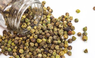 Tüm yeşil biberler şişeden dökülüyor. Fotokopi alanı olan beyaz arka plan.