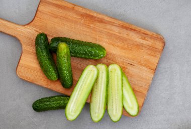 Salatalık turşusu, benekli gri üzerinde ahşap kesim tahtası.