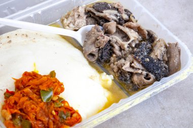 Geleneksel Güney Afrika Mogodo veya işkembe yahnisi seçici odaklı bir paket servis konteynırında pap ve chakalaka ile servis edilir.