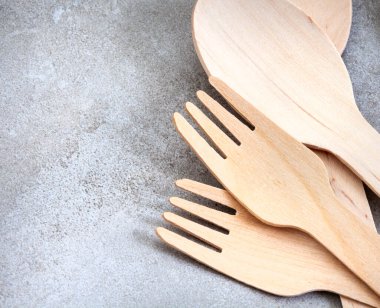 Açık gri grunge yüzeyinde ahşaptan yapılmış tek kullanımlık çatal bıçak takımı.