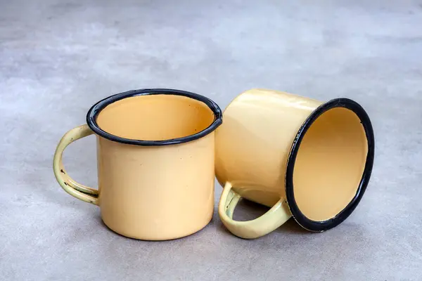 stock image Two small yellow enamelware cups on rustic grey surface with copy space