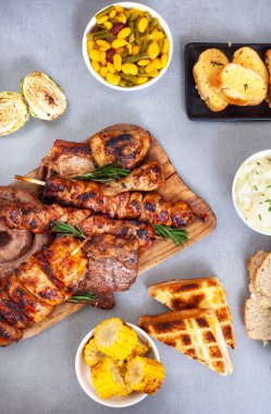 Geleneksel Güney Afrika Braai yemeğinin düzlüğü masada, et ve kenarları gri yüzeyde.