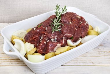 Çiğ biftek, patates, soğan ve sarımsak ile fırın için hazır.