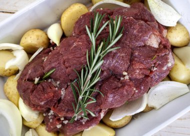 Çiğ biftek, patates, soğan ve sarımsak ile fırın için hazır.