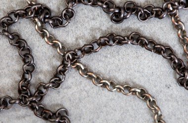 Açık gri beton dokuda siyah ve gümüş renkli zincirler.