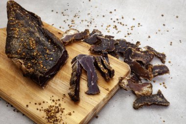 Büyük bir Güney Afrika biltong parçası. Gri üzerine dilimlenmiş parçalar ve kopyalama alanı var.