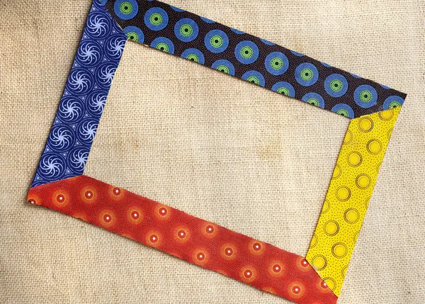 Farklı renkte kumaşlardan yapılmış renkli bir çerçeve. İkonik Güney Afrika pamuk baskı kumaşı. Altında kaba bir çuval bezi var.