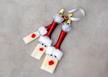 Üç farklı boyutta boya fırçası pamuk, göz ve ponpon ile süslenir. Böylece küçük boya fırçası Noel Baba süslemeleri yapılır. Gri bir yüzeyde bir sürü kopya alanı var.