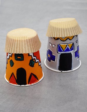 Kağıt bardaklar ve kek paketlerinden yapılmış iki Afrika ya da Ndebele kulübesi. Güney Afrika Miras Günü Gemisi