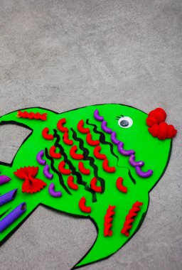 Detaylar için kullanılan renkli makarnalı yeşil karton balığın çocuk zanaatı..