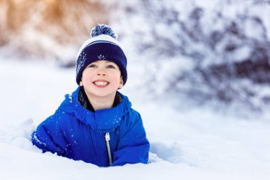 Sevimli küçük çocuk karda eğleniyor. Açık havada kış aktiviteleri çocuklar için