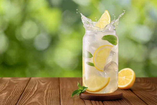 Glas Kalte Limonade Mit Spritzer Und Fallender Zitronenscheibe Auf Holztisch Stockfoto