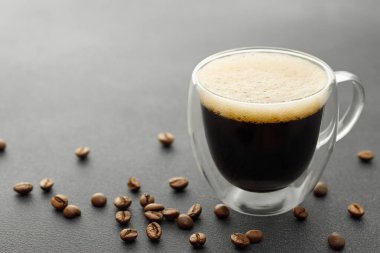 Duvar camlı espresso ve kahve çekirdekleri gri masada.