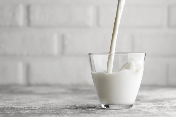 Молоко Наливається Склянку Сірий Стіл Білою Цегляною Стіною Фон — стокове фото