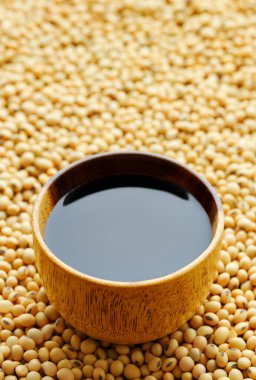 Arkaplan olarak kuru soya fasulyesi üzerine ahşap kasede soya sosu