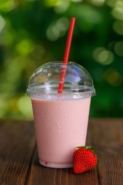 Çilekli milkshake ya da tek kullanımlık plastik bardakta açık havada saman olan smoothie.