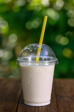 Vanilya aromalı milkshake veya tek kullanımlık plastik bardakta protein kokteyli.