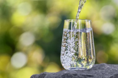 İçme suyu taşın üzerine dökülen yeşil doğal arkaplan.