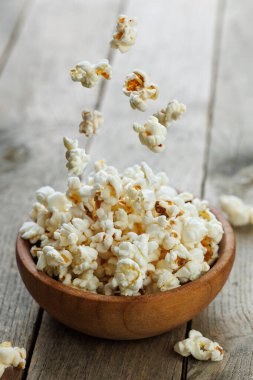 uçan patlamış mısır masadaki ahşap kaseye düşüyor.