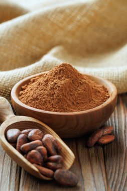 Kâsede kakao tozu ve tahta masada kakao çekirdeği kepçesi.