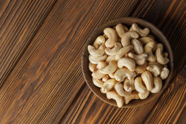 Kaju fıstıkları, sade ahşap masaya yerleştirilip sağlıklı atıştırma ve doğal yiyecek kavramlarını çağrıştıran sıcak ve davetkar bir sahne oluşturulur. Üst görünüm