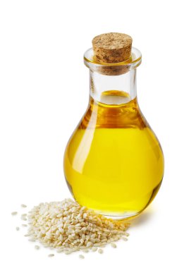 sesame oil in glass bottle with cork and heap seeds isolated on white background. Healthy eating concept