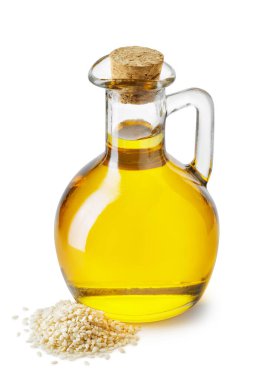 Cam sürahi içinde susam yağı ve beyaz arka planda izole edilmiş hurda tohumu. Sağlıklı yeme kavramı