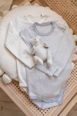 Flat lay composition bodysuit. Newborn baby clothes, accessories and toys set on neural beige background. Fashion Scandinavian newborn essentials. top view