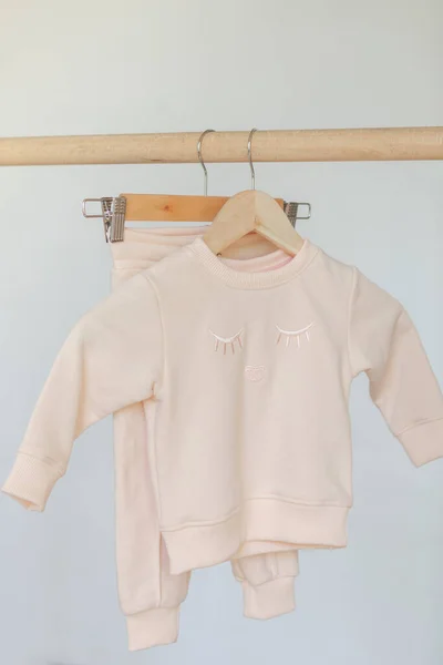 Aesthetic minimalist baby fashion.Wooden hanger for clothes with children\'s autumn outfit. pastel shades of children\'s clothing