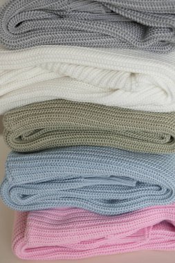 Cozy knitted warm pastel color sweaters background. Pile of colorful knit sweaters close up