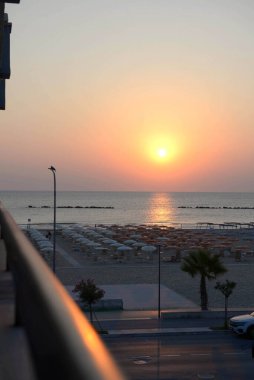 Denizin üzerinde güzel bir gün doğumu, otelin balkonundan manzara. Plaj tatilleri, güney şehri, İtalya, rahatlama, tatil planlama, Roseto degli Abruzzi. Arkaplan.