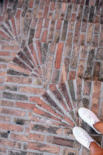 Old brick steps, top view, feet in white sneakers, hiking, streets of the old city, travel around Europe
