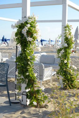Güzel manzara, sahildeki kafe, pergola. Beyaz kıvırcık çiçekler, deniz, tatil. Otel, lüks
