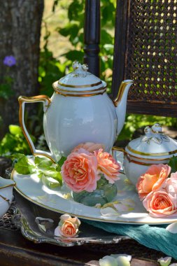 Beyaz porselen çaydanlık çay, yazın bahçede çay partisi, güzel bir ortam, güller, antika porselenler, İngiliz geleneği.