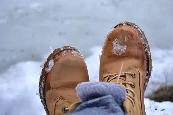 Feet in boots close-up, walking in the snow, comfortable shoes, seasonal shoes, brown suede boots, nubuck, trekking, waterproof shoes, background, concept