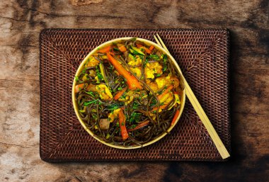 Top view of Soba beef and vegetables, buckwheat noodles on a old wooden table background. Traditional asian food.