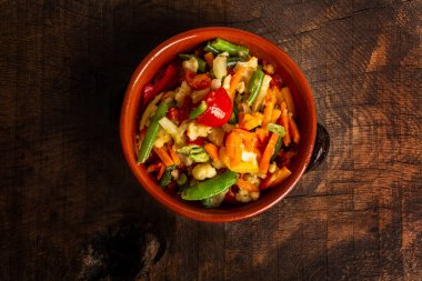 Mediterranean Vegetables in terracotta dish on old wooden table. Natural nutrition concept. Top view.
