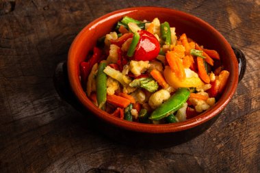 Mediterranean Vegetables in terracotta dish on old wooden table. Natural nutrition concept. Top view.